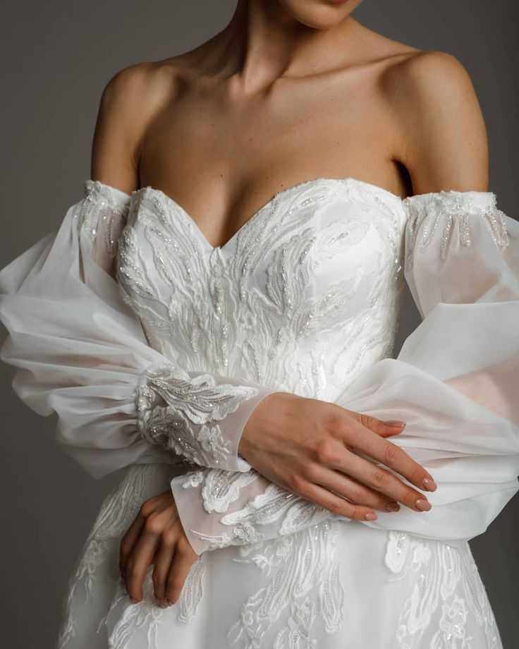Невеста может выбрать свадебное платье с открытыми плечами - пышное или приталенное Оно смотрится очень красиво и женственно Этот наряд подходит девушкам с разными типами фигуры